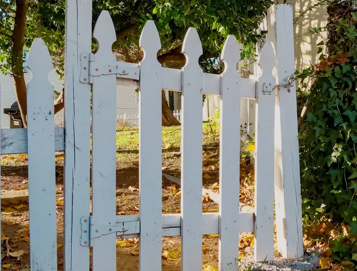 A white picket fence and gate, seen close, with the slats running to about waist height