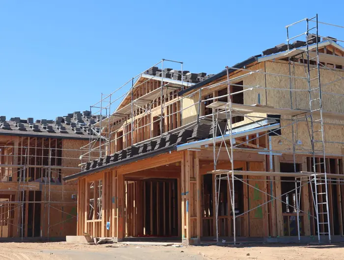 A timber framed house part way through construction, still in scaffolding