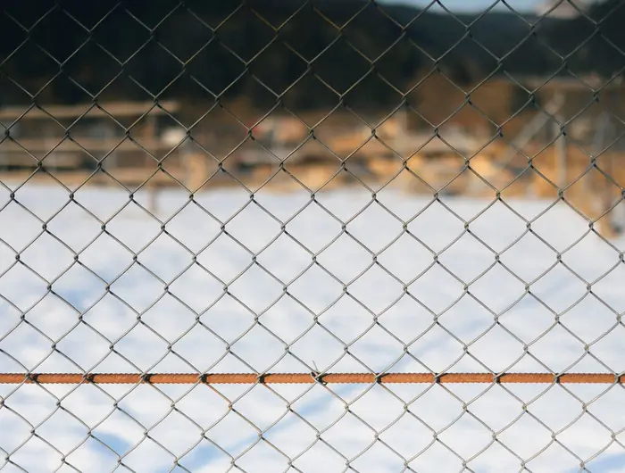 A chain link fence running along a boundary against an open sky